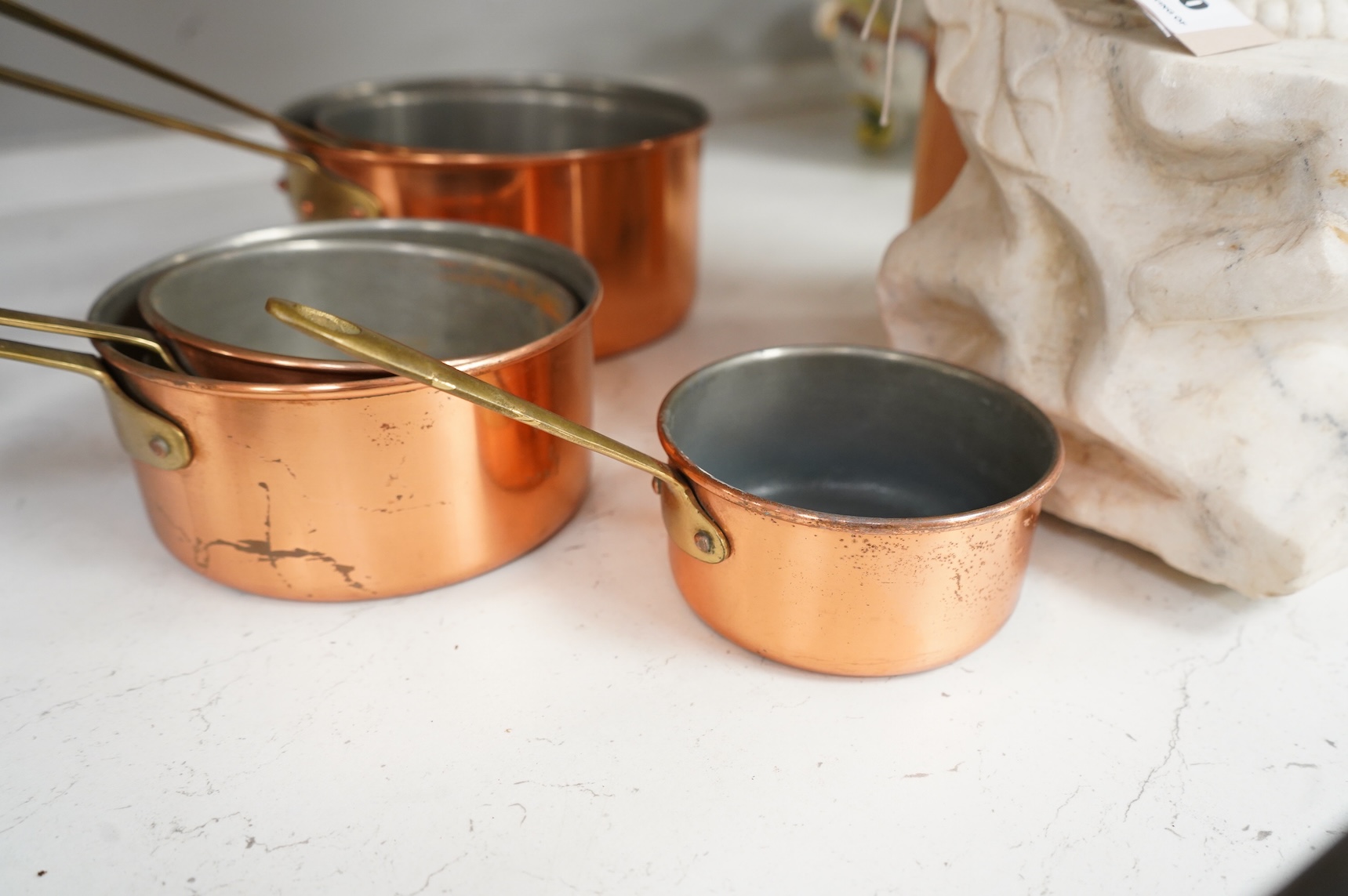 A graduated set of five brass handled copper saucepans, largest 36cm including handle.